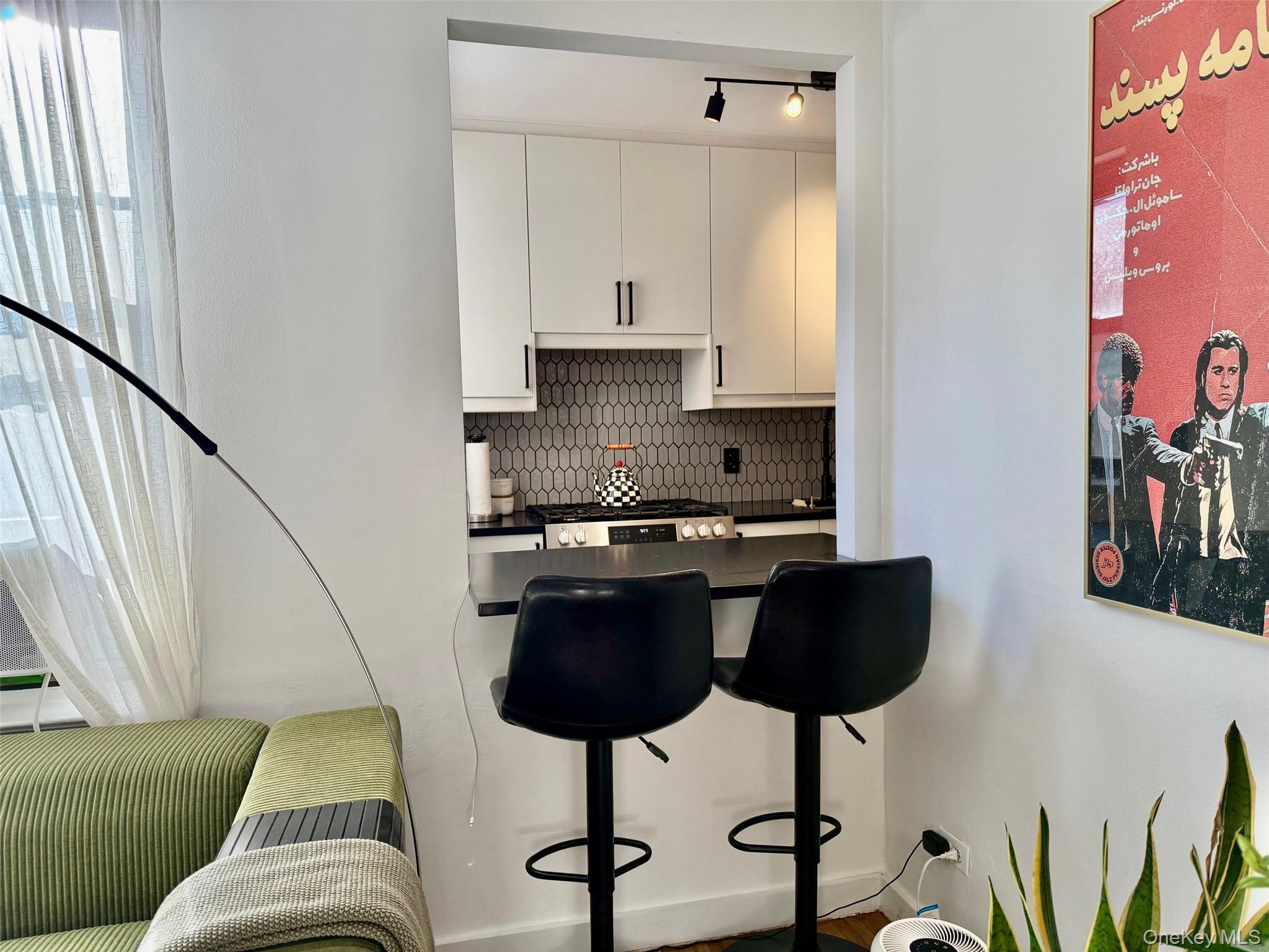 112-30 Northern Boulevard, Unit 2A Queens, NY 11368 - Photo 11 of 40 Kitchen with a breakfast bar area, dark countertops, white cabinets, decorative backsplash, and stainless steel gas range