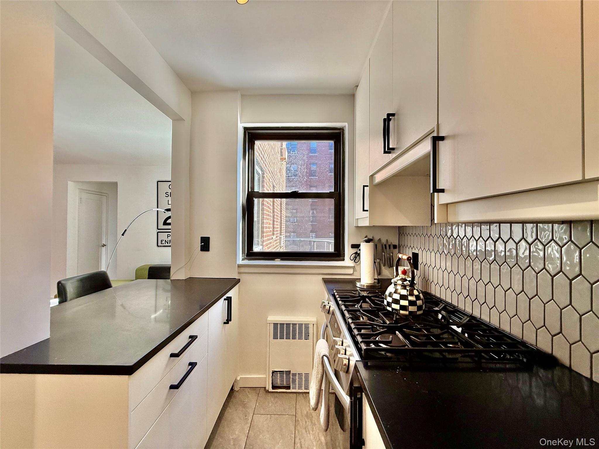 112-30 Northern Boulevard, Unit 2A Queens, NY 11368 - Photo 6 of 40 Kitchen with white cabinetry, gas stove, modern cabinets, and backsplash