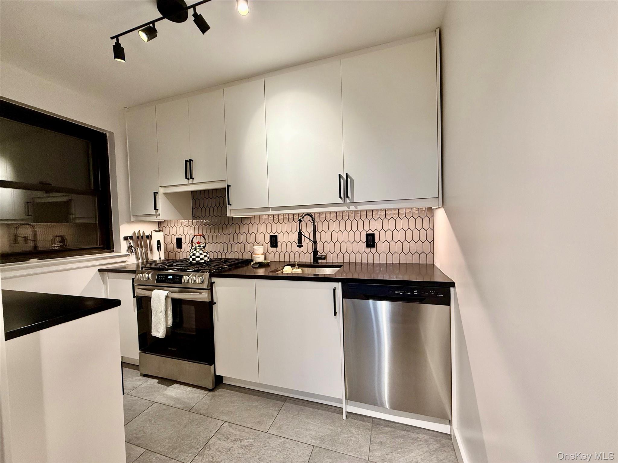 112-30 Northern Boulevard, Unit 2A Queens, NY 11368 - Photo 7 of 40 Kitchen with appliances with stainless steel finishes, white cabinets, backsplash, and light tile patterned floors