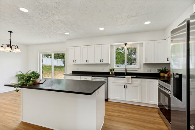 62 South Clark Lane Elk Ridge, UT 84651 - Photo 8 of 30 Modern kitchen featuring a central island with a dark countertop, white cabinetry with dark hardware, stainless steel appliances, and LVP flooring
