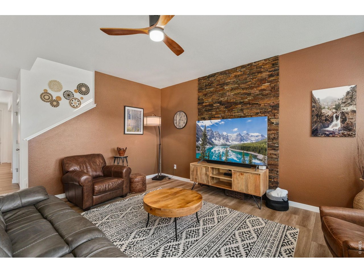 438 Bluebird Road Johnstown, CO 80534 - Photo 14 of 33 Stone feature wall, mounted-TV space, and sectional seating open to the kitchen.