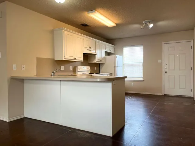 a kitchen with kitchen island granite countertop a sink cabinets and wooden floor