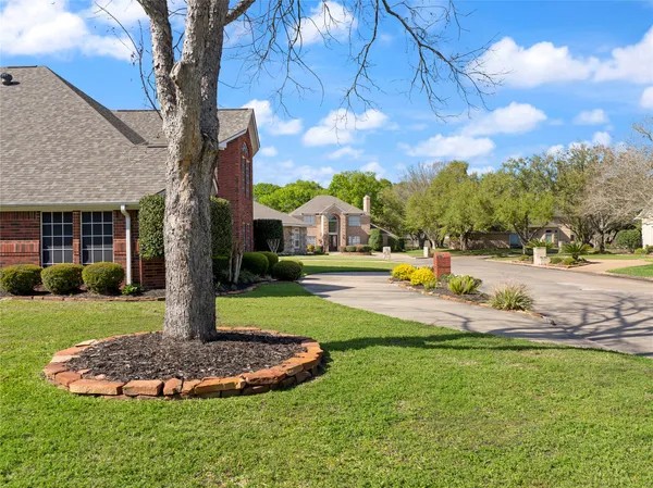 a front view of a house with a yard fountain and large tree