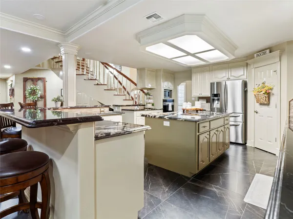 a kitchen with sink a refrigerator and chairs