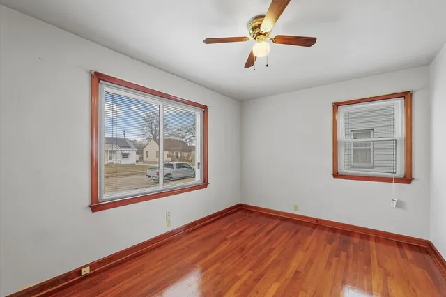 a view of an empty room with window and wooden floor
