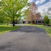 a view of a house with a big yard and large trees