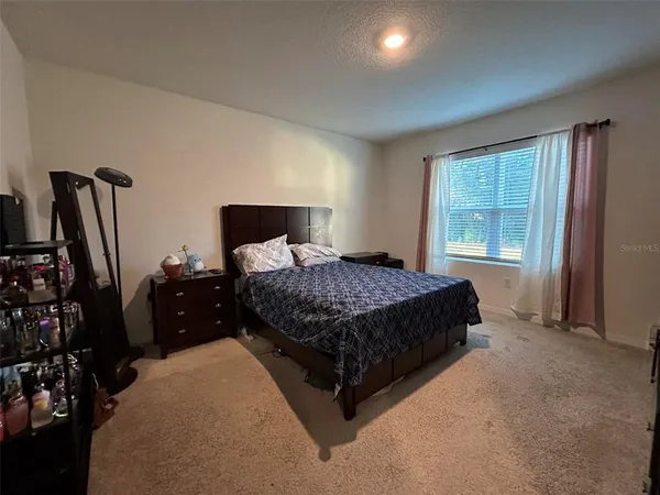 a bedroom with a bed and a flat tv screen on a dresser