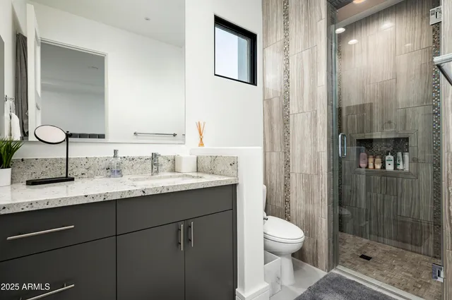 a bathroom with a granite countertop sink toilet a mirror and shower