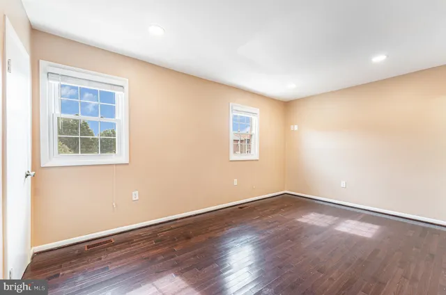 an empty room with wooden floor and windows