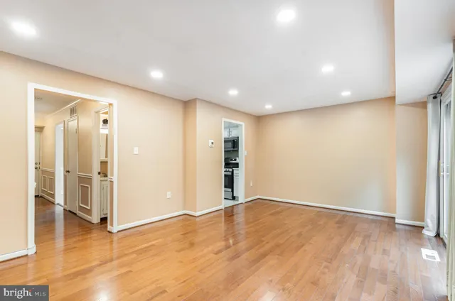 an empty room with wooden floor and entrance to other room