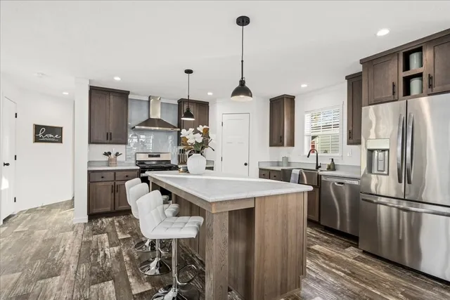 a kitchen with stainless steel appliances a stove a sink a refrigerator a center island and chairs