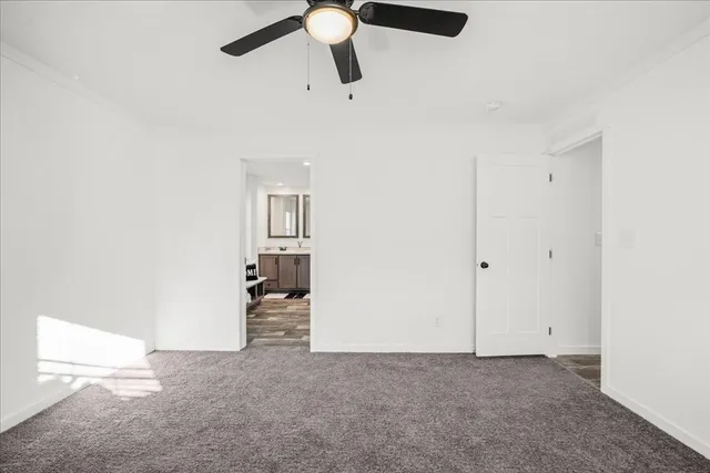 an empty room with chandelier fan and windows