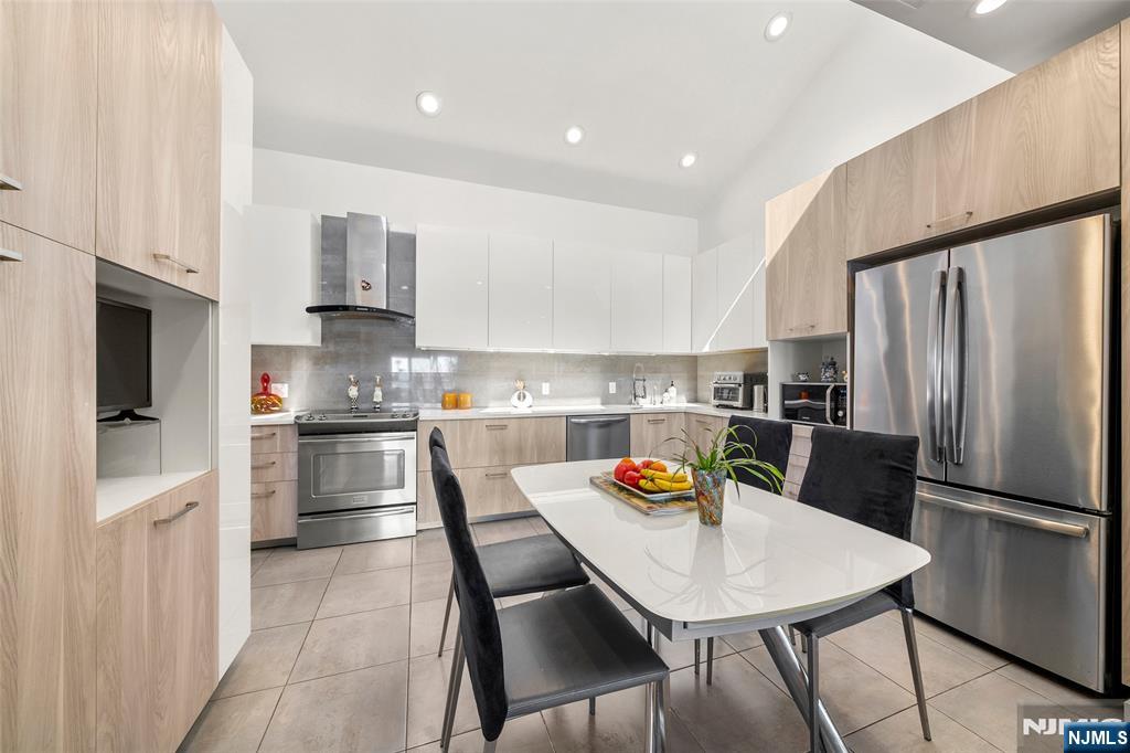 300 Gorge Road, Unit 58 Cliffside Park, NJ 07010 - Photo 8 of 32 a kitchen with stainless steel appliances granite countertop a sink a stove a refrigerator cabinets and a dining table