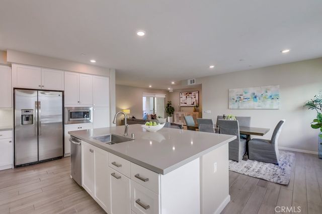 a large kitchen with kitchen island a dining table chairs stainless steel appliances and wooden floor