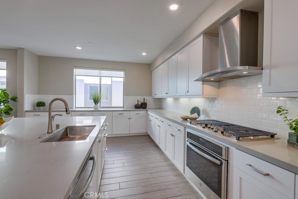 136 Tribeca Irvine, CA 92612 - Photo 8 of 70 a kitchen with kitchen island a sink stove top oven and cabinets