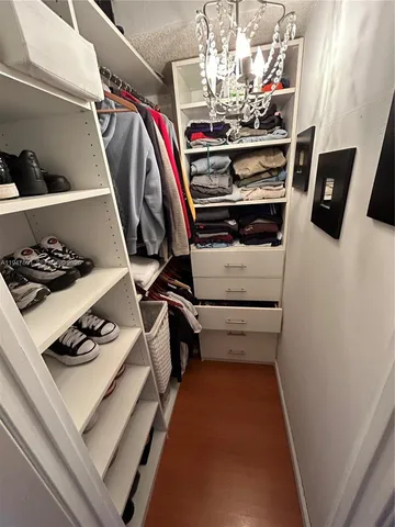 a view of walk in closet with clothes and shoes