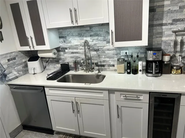 a kitchen with white cabinets a sink and white appliances