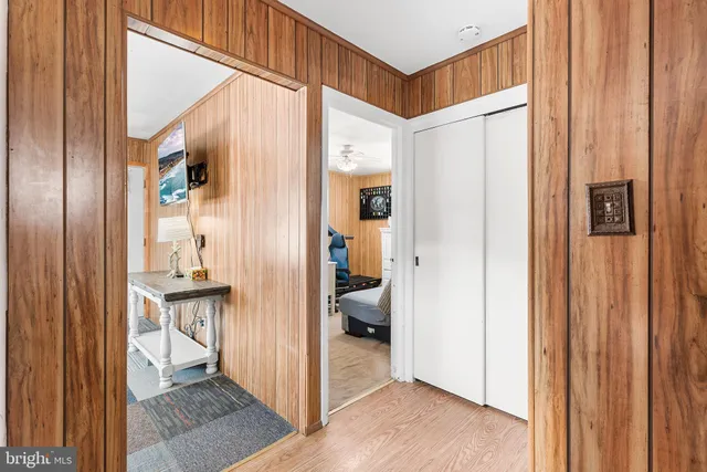 a view of hallway with wooden floor and a bathroom