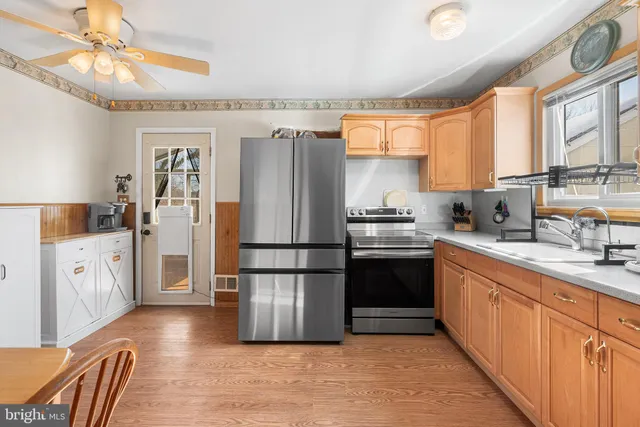 a kitchen with a refrigerator a stove a sink dishwasher and a dining table with wooden floor