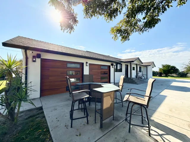a backyard of a house with wooden floor barbeque oven table and chairs