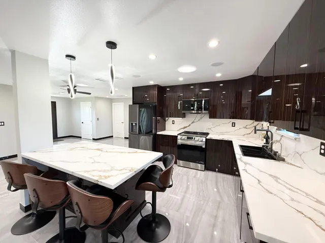 a large kitchen with stainless steel appliances kitchen island granite countertop a refrigerator and a sink