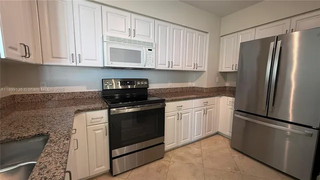 a kitchen with granite countertop white cabinets stainless steel appliances and a sink