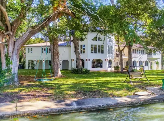 a front view of a house with a garden and trees