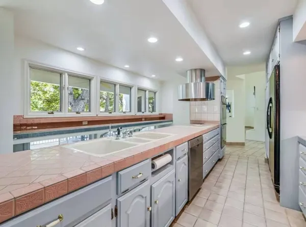 a large kitchen with a large counter top a sink a refrigerator and a counter top space