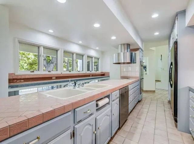 a large kitchen with a large counter top a sink a refrigerator and a counter top space