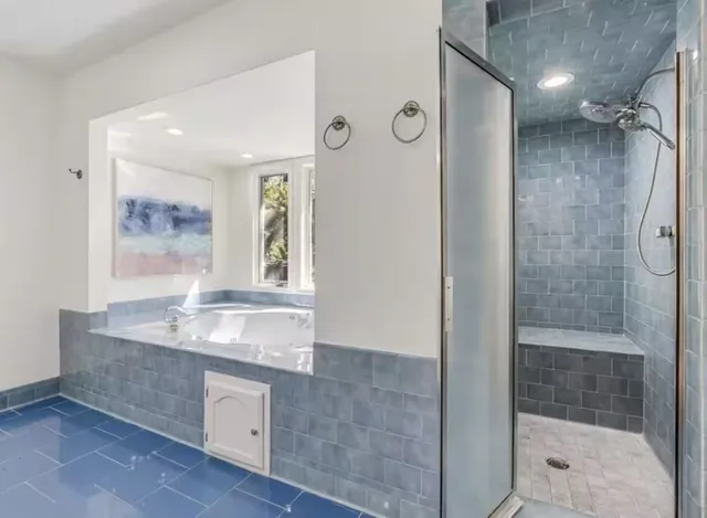 a bathroom with a granite countertop sink a mirror a window and a shower