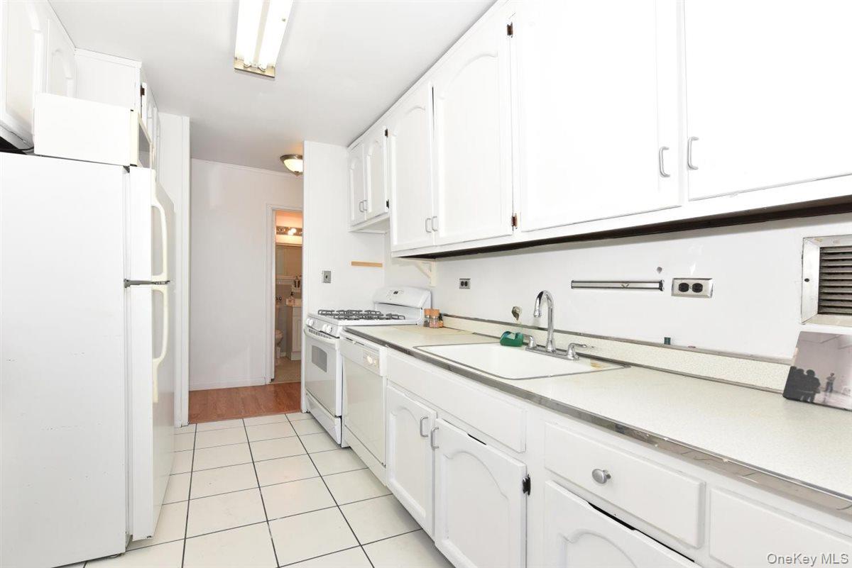 175-20 Wexford Terrace, Unit 16L Queens, NY 11432 - Photo 6 of 26 a kitchen with a sink a refrigerator and cabinets