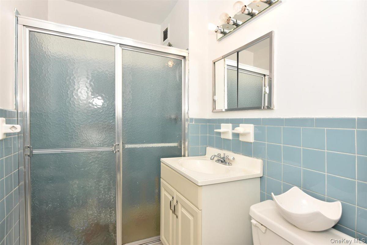 175-20 Wexford Terrace, Unit 16L Queens, NY 11432 - Photo 8 of 26 a bathroom with a sink a toilet and shower