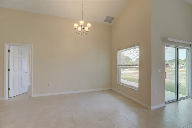 an empty room that has a chandelier fan and windows