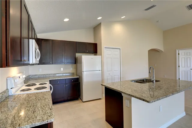 a kitchen with stainless steel appliances granite countertop a refrigerator and a stove top oven