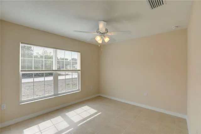 an empty room with a chandelier fan and windows