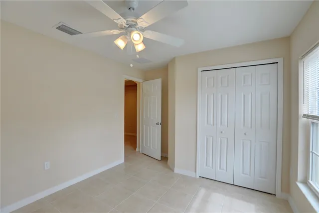 an empty room with windows and fan