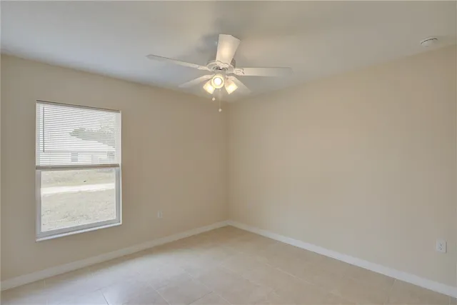 an empty room with a chandelier fan and a bathroom