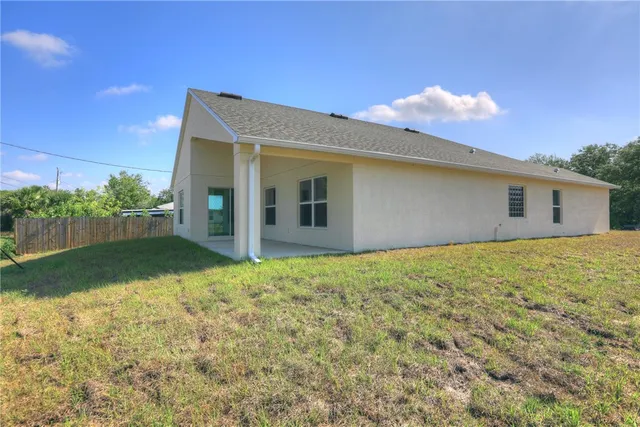 a backyard of a house with plants and large tree