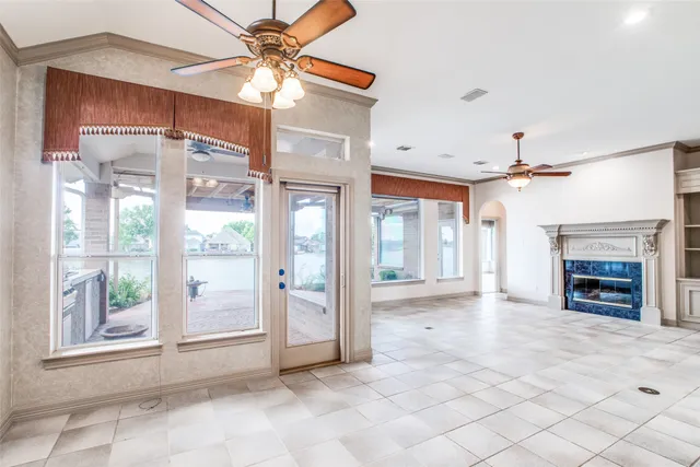 a view of a livingroom with a fireplace a ceiling fan and windows