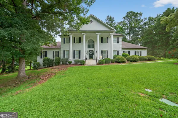 a front view of a house with a garden and trees