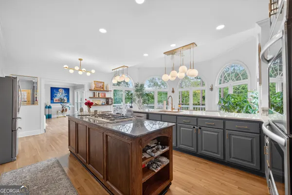a kitchen with stainless steel appliances granite countertop a stove refrigerator a sink dishwasher and a dining table with wooden floor