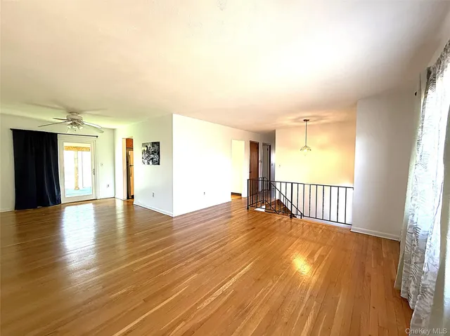 a view of an empty room with window and wooden floor