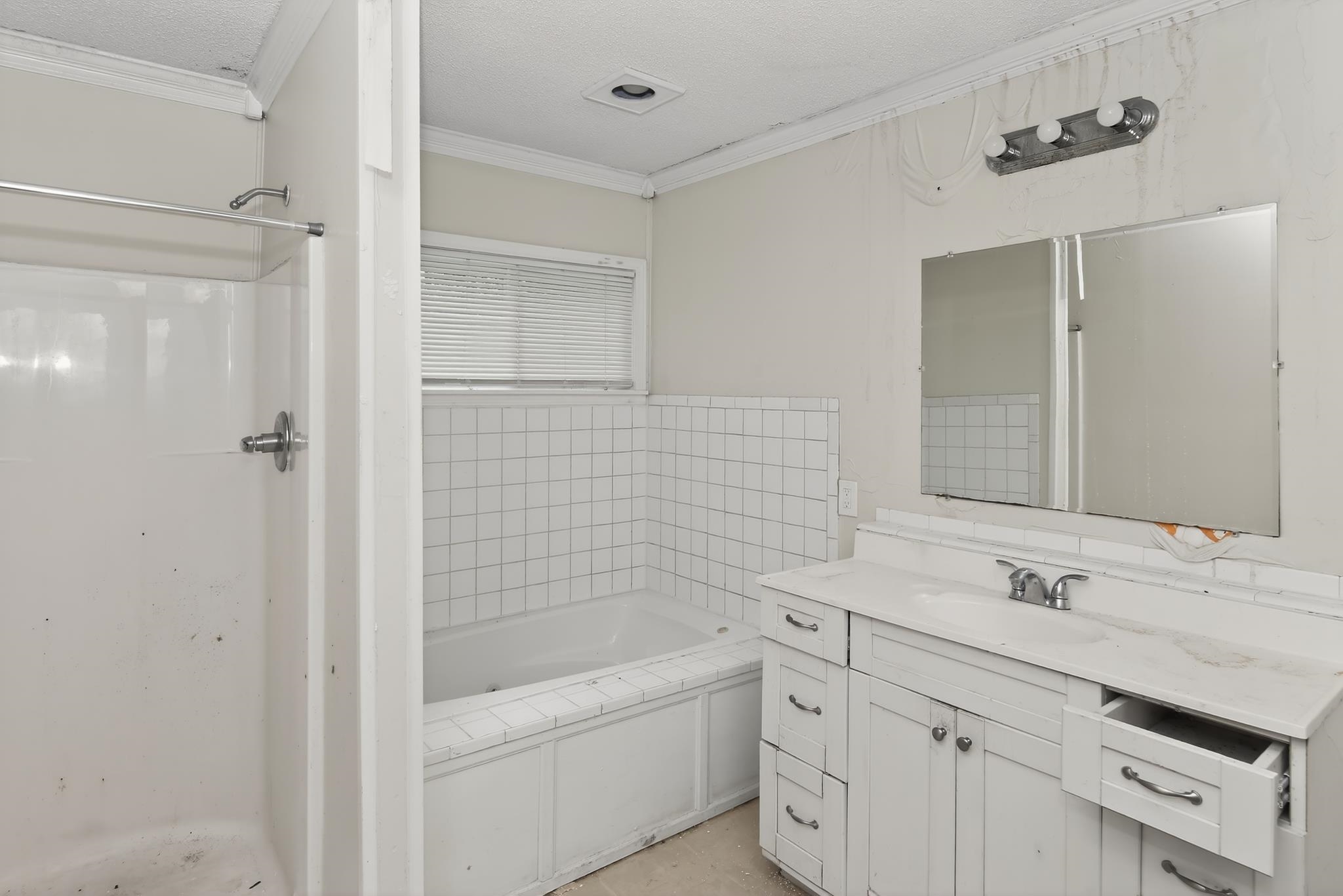 1403 Old Hickory Road Memphis, TN 38116 - Photo 21 of 31 Bathroom featuring a built-in tub with white tile surround, a separate shower stall with chrome fixtures, a vanity with a white countertop and integrated sink, a large wall-mounted mirror, and a horizontal window with blinds