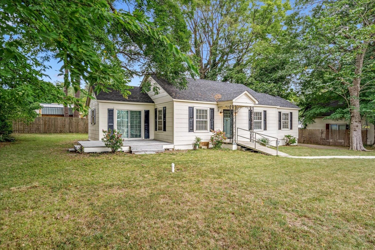 a backyard of a house with table and chairs and wooden fence