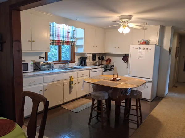 a kitchen that has a table chairs and a refrigerator