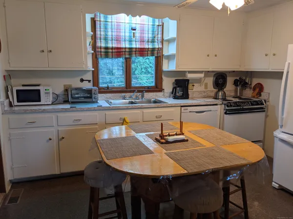 a kitchen with stainless steel appliances granite countertop a stove a sink dishwasher a stove a dining table and chairs