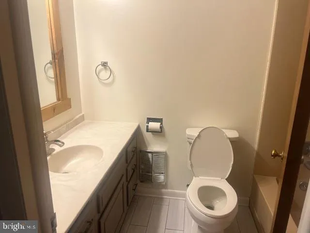 a bathroom with a granite countertop toilet sink and mirror