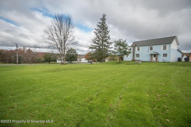 a view of a house with a big yard and large trees