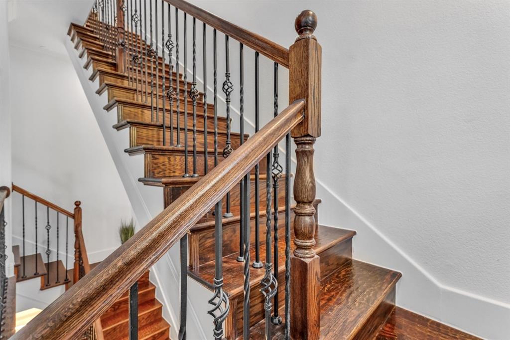 5744 Robbie Road Plano, TX 75024 - Photo 21 of 32 Staircase featuring dark wood treads and risers, wrought iron balusters with decorative twists, a substantial wood newel post, and a matching wood handrail