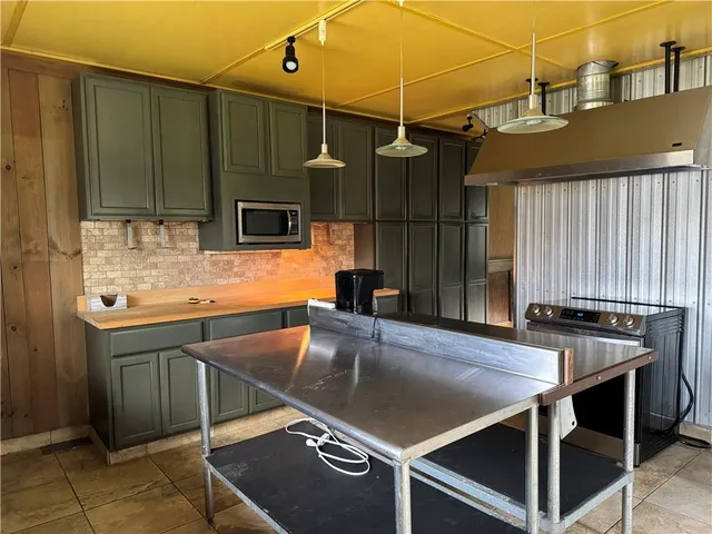 a kitchen with kitchen island a large counter top space appliances and a window
